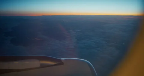 Aircraft Window View Above Clouds at Dusk with Golden Horizon Stock Footage 343592862