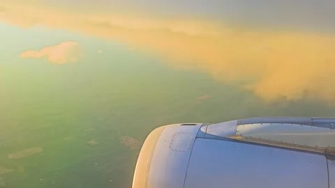 Aircraft window view of dark rain clouds and warm golden light over land below Vídeos de archivo 334639328