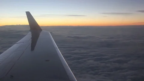 Aircraft wing and clouds as seen from a commercial jet window at sunset. Stock Footage 128780353