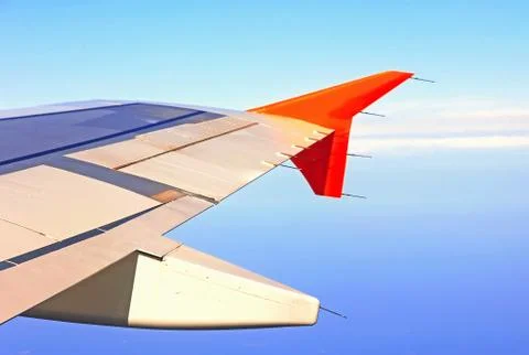 Aircraft wing in flight, view from the window at the blue sky airplane flying Stock Photos