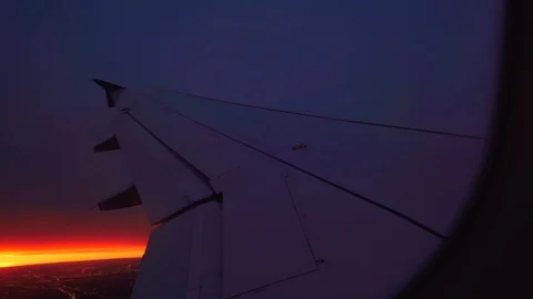 Aircraft wing seen through window against sky during sunset, Aerial shot of Stock Footage 128848590