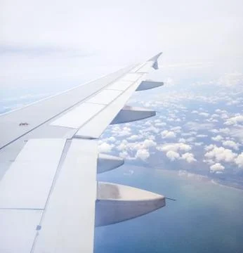 Aircraft wing view from airplane window seat. Beautiful sky with sunlight and Stock Photos