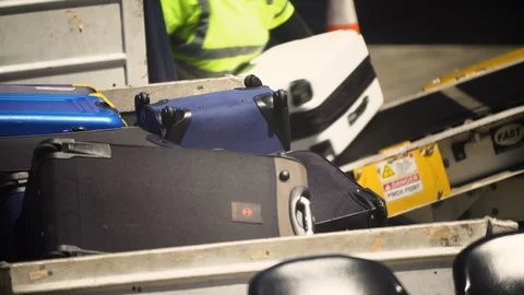 Airline ground crew unload checked luggage from tarmac conveyor belt onto truck Video stock 115517358