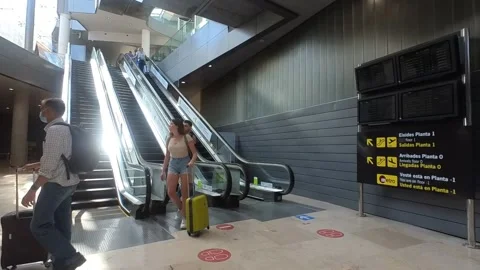 Airline Passengers going down an escalator in the Airport in Valencia, Spain Stock Footage 195453954