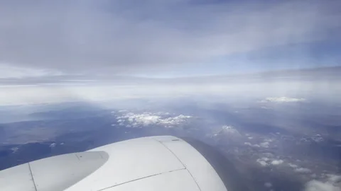 Airliner flying in clouds above the ground, view through the porthole window on Stock Footage 316701206
