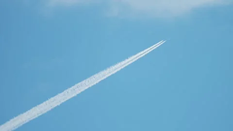 Airliner flying high leaving long white contrail across blue sky, aviation route Vidéo 337637798