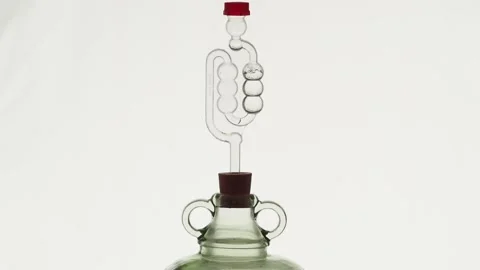 Airlock on top of demijohn with bubbles due to fermentation Stock Footage 157444227