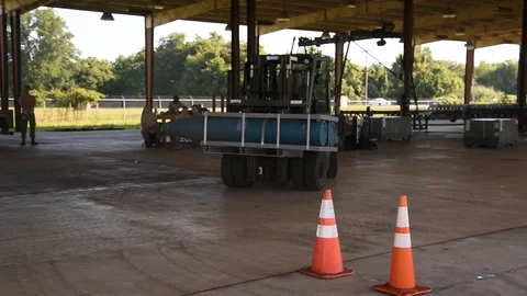 Airman positioning crate of bombs between traffic cones with forklift truck Stockbeeldmateriaal 113394706