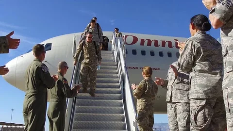 Airmen applaude as airmen returning from deployment descend steps of aircraft Stock Footage 113394538
