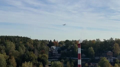 Airplane approaching for landing over city with smoking chimney and autumn .. Stock Footage 318544432