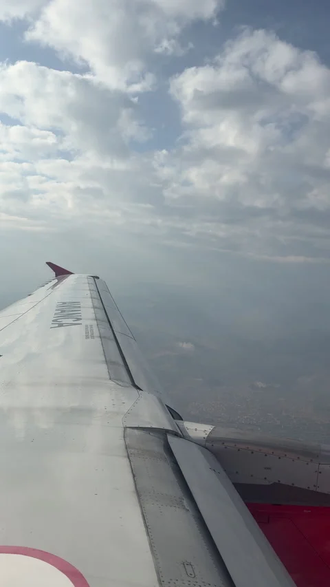 Airplane Avianca Wing Over Cloudy Skies with Distant Landscape Below Stock Footage 336979406