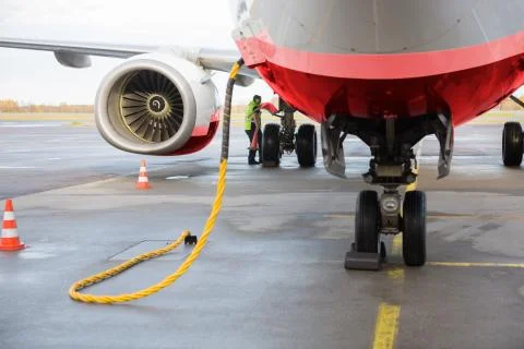 Airplane Being Charged While Worker Working On Runway 写真素材