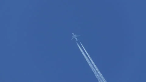 Airplane in blue sky with contrails behind passing by Stock Footage 313380671