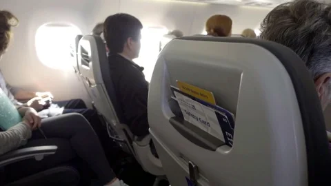 Airplane cabin interior with passengers sitting in seats on bright sunny day Vidéo 70139811