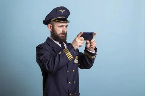 Airplane captain using smartphone to watch videos on screen in studio Stock Photos