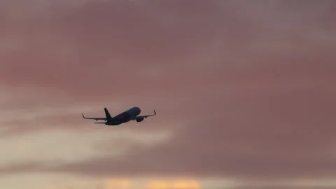 Airplane climbing into a pink sunset sky after takeoff Stock Footage 337797217