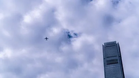 Airplane in cloudy sky with skyscraper Stock Photos