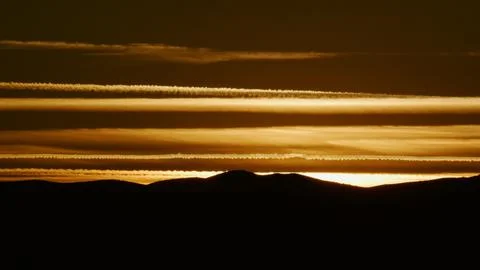 Airplane contrails cut an array of geometric lines at sunset. Foto stock