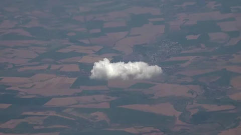 Airplane crosses above patterned farmland and soft cumulus - Country Landscape Stock Footage 339645682