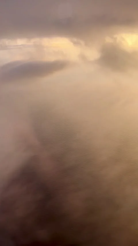 Airplane descending through golden clouds at sunrise Stock Footage 344412774