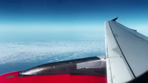 Airplane engine seen from window above a soft cloud layer during flight in Stock Footage 342030827