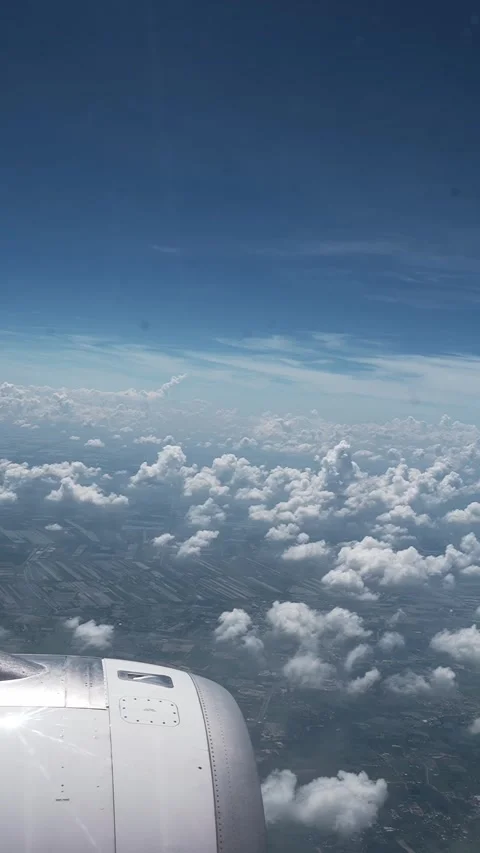 Airplane engine view above clouds and patchwork farmland from window Stock Footage 348046378