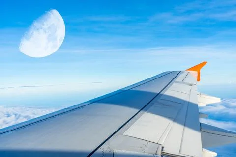 The airplane evening sky view with half moon, view above ocean from cabin win Stock Photos