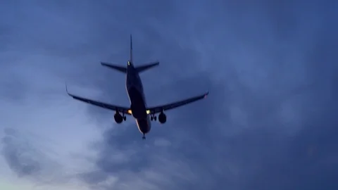 Airplane flies overhead. Close-up. Evening. Dark blue clouds in the background Stock Footage