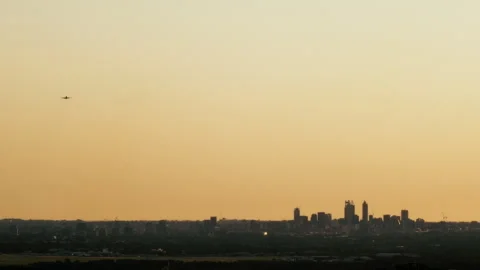Airplane flies in the sky above the Perth skyline Stock Footage 345668846