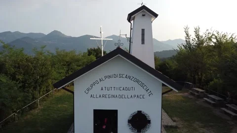 Airplane flight backwards taking back a church built by the Italian Alpini Stock Footage 157654765