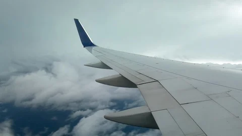 AIRPLANE FLIGHT LOOKING OUT WINDOW OVER WING TOWARDS CLOUDS AND OCEAN Stock Footage 92717951