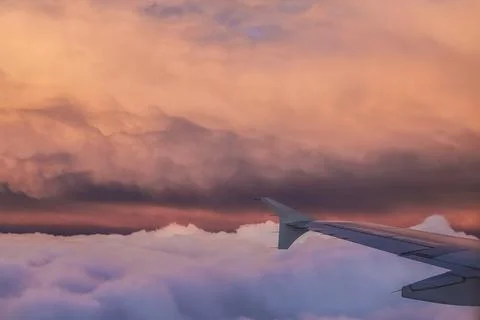 Airplane flight over the clouds at sunset Stock Photos