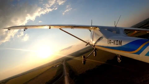 Airplane in flight, showcasing the wing and landscape below, as the sun sets Stock Footage 319747933