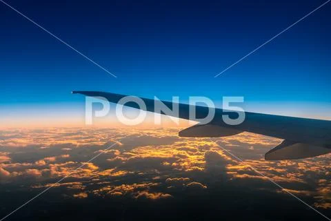 The airplane fly in the evening sky on the background of beautiful clouds Stock Photos