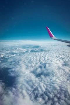 Airplane flying above clouds in dramatic sunset light Stock Photos