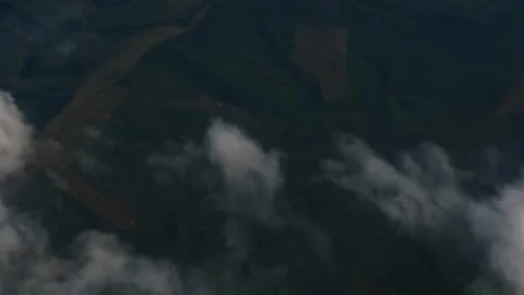 Airplane flying above clouds over green hills and fields Video stock 343925864