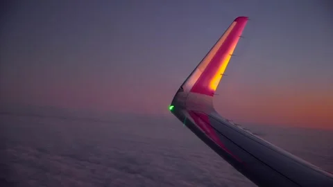 Airplane flying above clouds at sunset with illuminated wingtip and soft Stock Footage 335369311