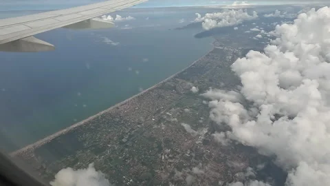 An airplane flying above the clouds. View of the city and the seashore. Stock Footage 329507109