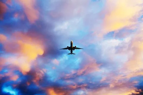 Airplane flying above dramatic clouds during sunset,sunrise. Stock Photos