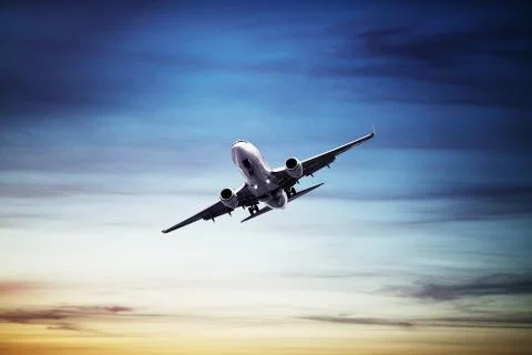 Airplane flying above dramatic clouds during sunset,sunrise. Fotos Stock