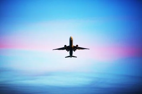 Airplane flying above dramatic clouds during sunset,sunrise. Stock Photos