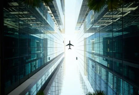 Airplane flying above glass office buildings. Stock Photos