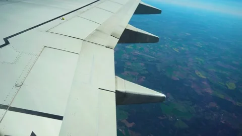 Airplane flying above patchwork fields with visible wing and flap support 스톡 동영상 319759607