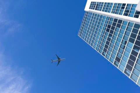 Airplane flying above a skyscraper Stock Photos