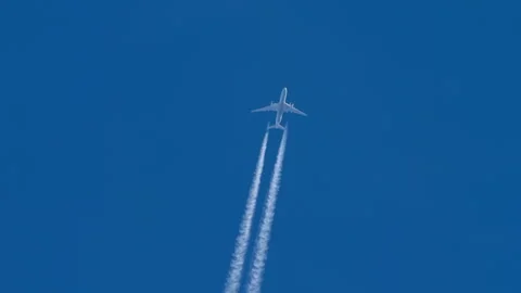 Airplane flying and leaving white contrail in clear blue sky Stockbeeldmateriaal 338129133