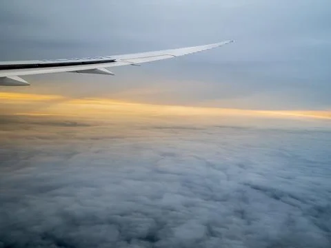 Airplane flying between cloud layers viewed from passenger cabin window Stock Photos