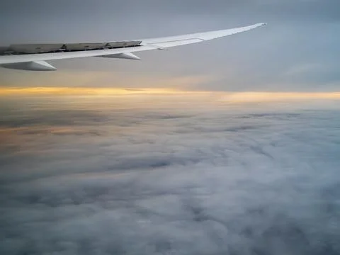 Airplane flying between cloud layers viewed from passenger cabin window Stock Photos