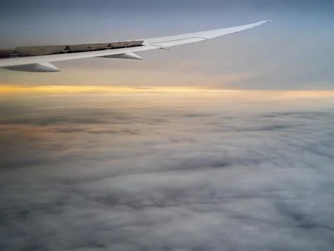 Airplane flying between cloud layers viewed from passenger cabin window Stock Photos