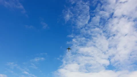 Airplane flying in a blue cloudy sky Stock Footage 288709707