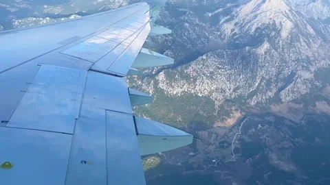 Airplane flying on blue sky above mountains. A view on airplane wing from the Stock Footage 201320153